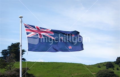 New Zealand Flag with green countryside behind