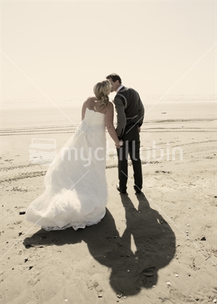 bridge and groom kissing on the beach after their wedding