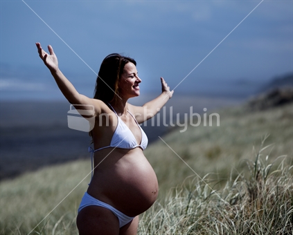 A pregnant woman enjoying the sun at the beach