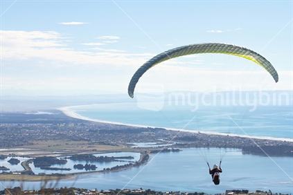 Paraglider flying over the coast at Christchurch, South Island.