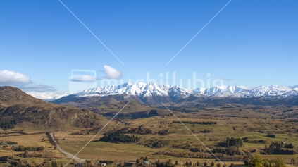 Panorama of snow capped mountain and green field near Queenstown in New Zealand.
