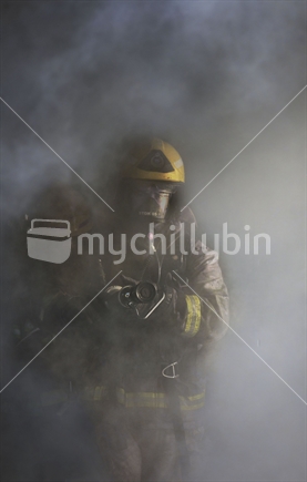 A member of the local volunteer fire department putting out a house fire.