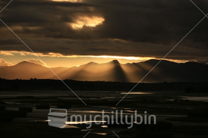 Dark cloudy sky with the sun setting over the mountains