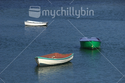 Three dinghies moored on the water on a calm day