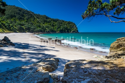 Secluded Homunga Bay in the Coromandel with a person standing on the rocks.