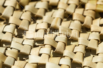 Sideways closeup of a woven mat made of windmill knot - traditional New Zealand flax weaving