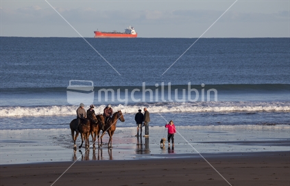 Horses on beach with ship and waves in background