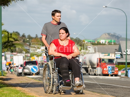 Man pushing woman in wheelchair