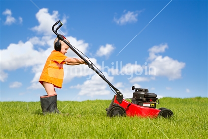Little boy mowing the lawn