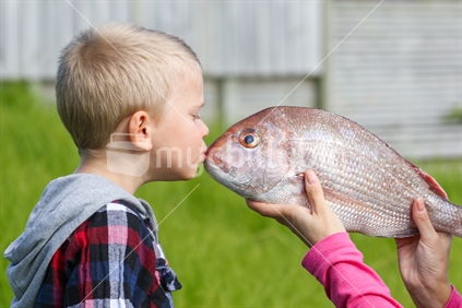 Little boy kissing snapper fish