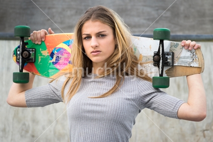 Pretty teenage girl holding skateboard