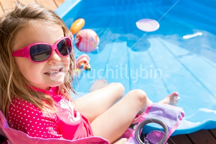 Little girl sitting next to blue shell pool
