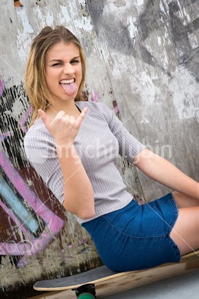 Pretty teen girl giving rock on sign hand gesture