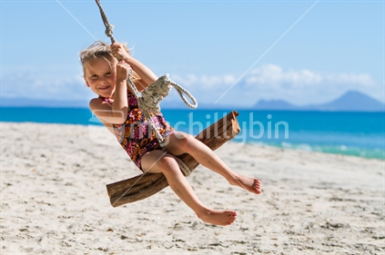 Child playing on swing at beach