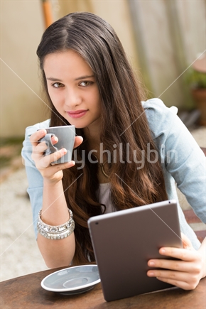 Young Maori woman using difital tablet drinking coffee