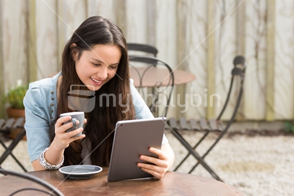 Maori woman using digital tablet drinking tea