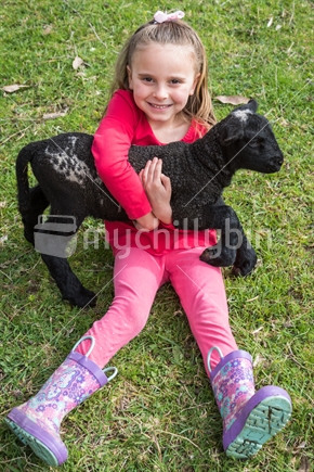 Girl holding newborn black lamb