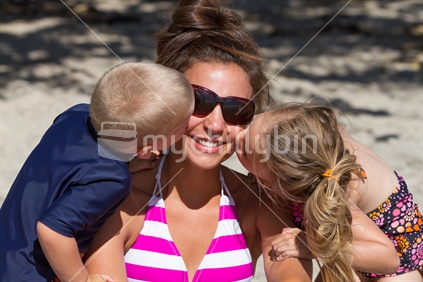 Children kissing mum at the beach