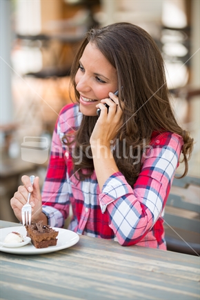 Woman eating cake talking on phone