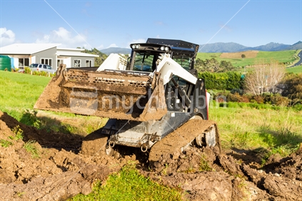 Mini digger digging up ground