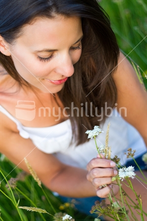 Beautiful young woman picking wild flowers