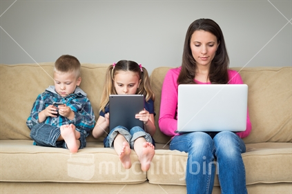 Family sitting on couch using digital devices