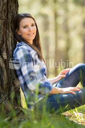 Beautiful woman sitting against tree