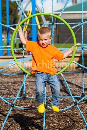 Little boy playing on playground jungle gym