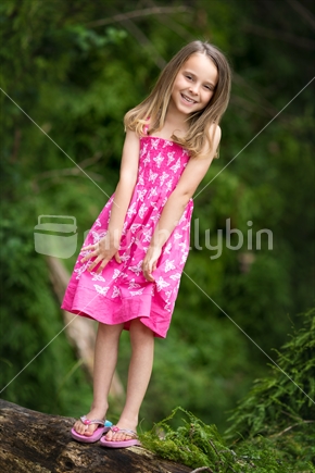 Pretty blond girl standing on a log in the bush