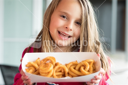 Young girl holding curly fries