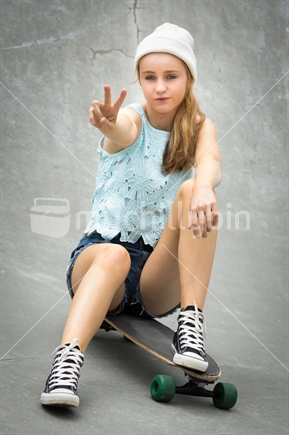 Teen skater girl giving peace sign