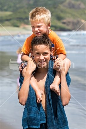 Boys giving piggyback ride at the beach