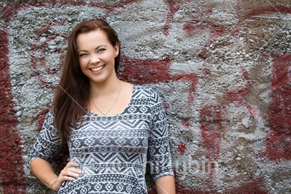 Beautiful smiling woman leaning against wall