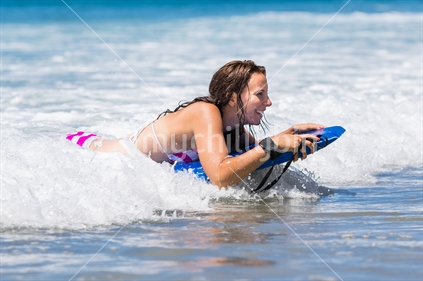Beautiful young woman riding boogie board