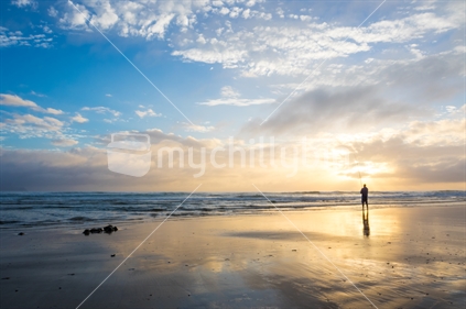 Man fishing on the beach at sunrise (Foreground focus)