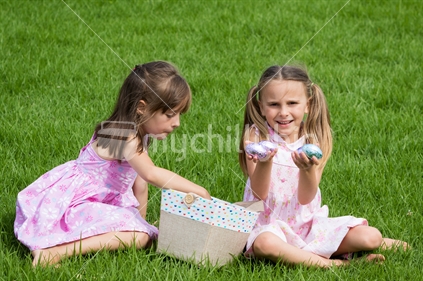 Two girls with easter eggs in grass