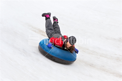 Woman riding snow tube down hill