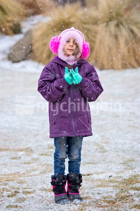 Little girl playing in the falling snow
