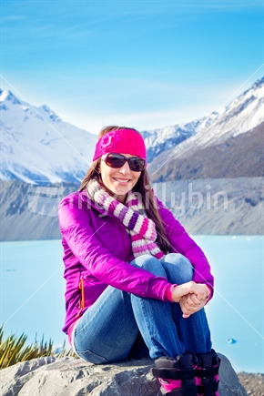 Young woman sitting by lake Tasman in winter