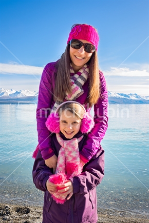 Mother and daughter by the lake in winter clothes