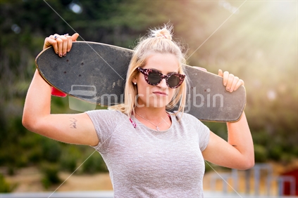 Pretty blond skater girl holding skateboard