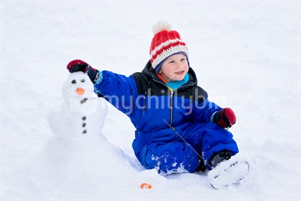 Little boy building a snowman