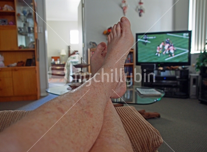 Typical kiwi posture, older adult, vegging out on the recliner watching rugby on a Saturday afternoon