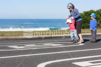 Family walking down a deserted road by the beach (John Wilson Drive, Dunedin).