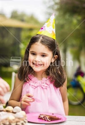 Girl with a party hat at a birthday party.
