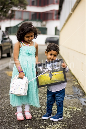 Boy holding his present as his older sister looks on in admiration.