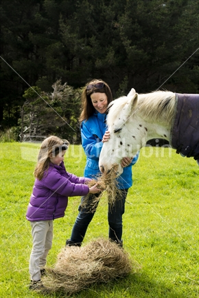 Mother and daughter feeding horses