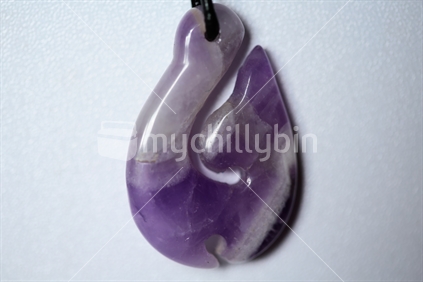 A purple glass fish hook pendant.