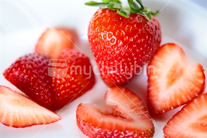A high view of a mixed of whole and sliced strawberries.