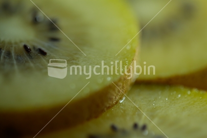 Close up of gold kiwi fruit slices.  With the skin of the fruit showing.